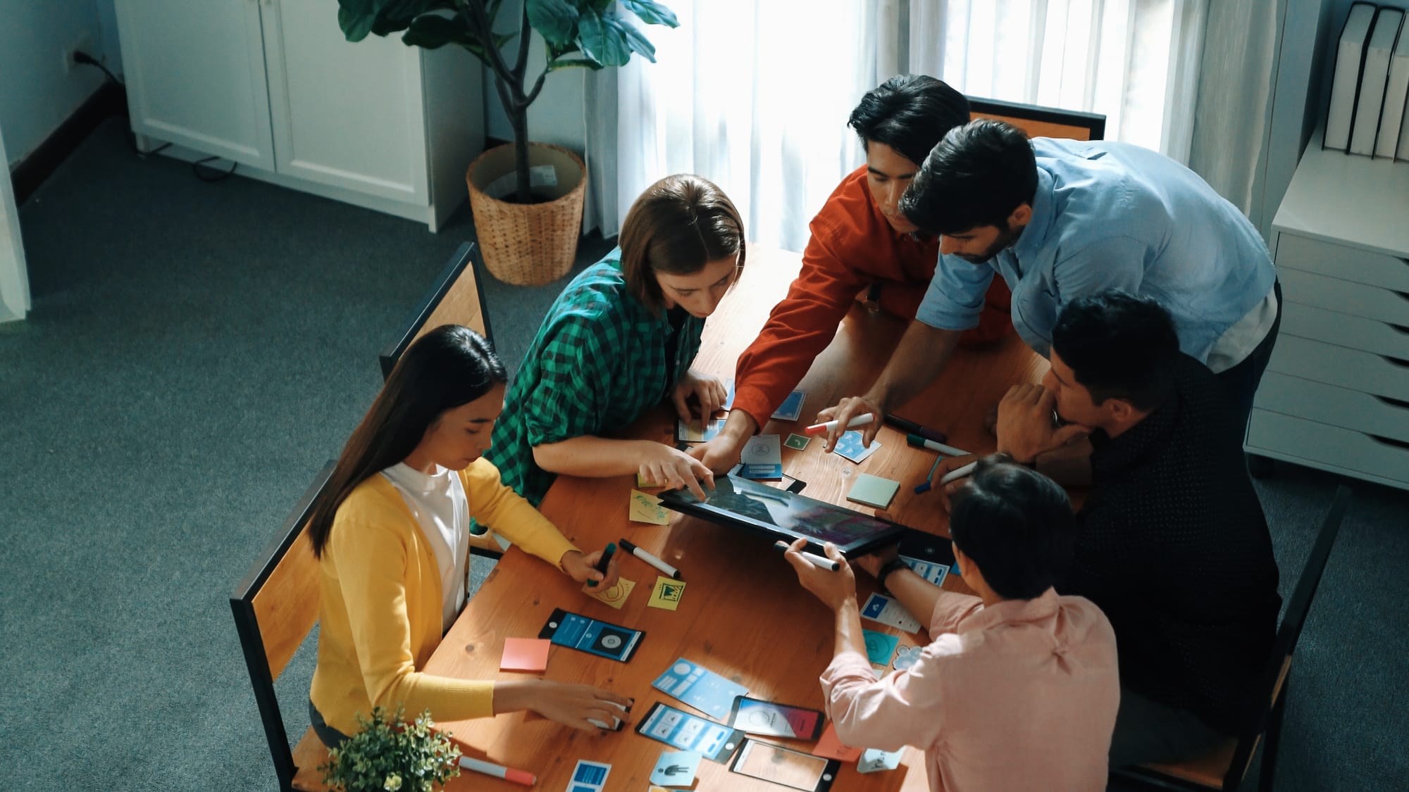 Líder em pé, participando ativamente de uma reunião, compartilhando ideias de UX/UI com a equipe